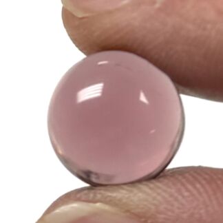 Close-up of a small pink round cabochon bead held between fingers.