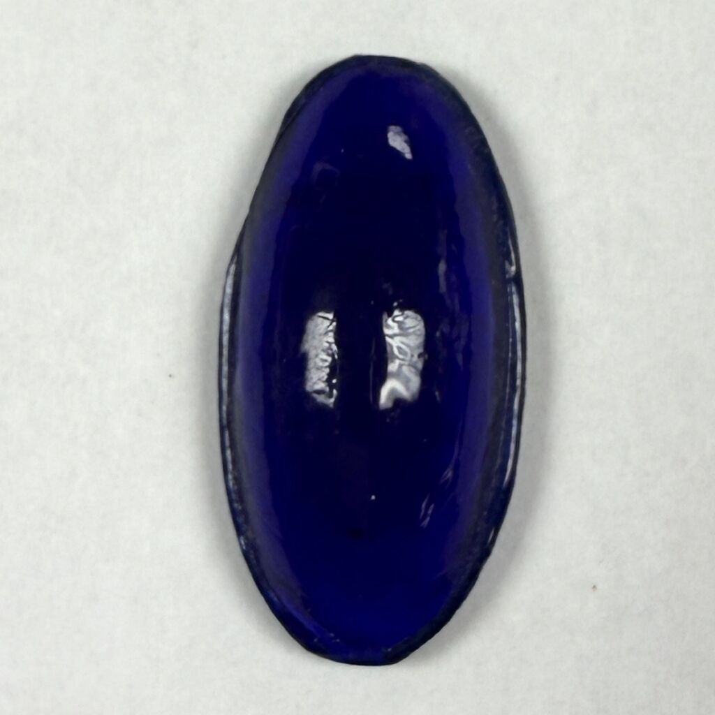 Deep blue oval cabochon gemstone on a light background.